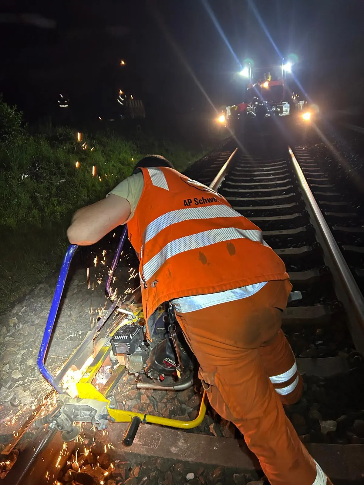 Mitarbeiter bei Schienenbearbeitung mit Schleifgerät im Gleis